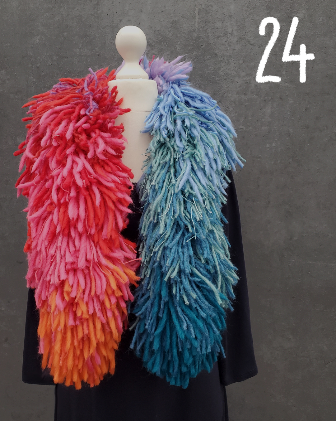 Schneiderpuppe mit dunkelblauem Kleid und einer bunten Fransenboa um den hals